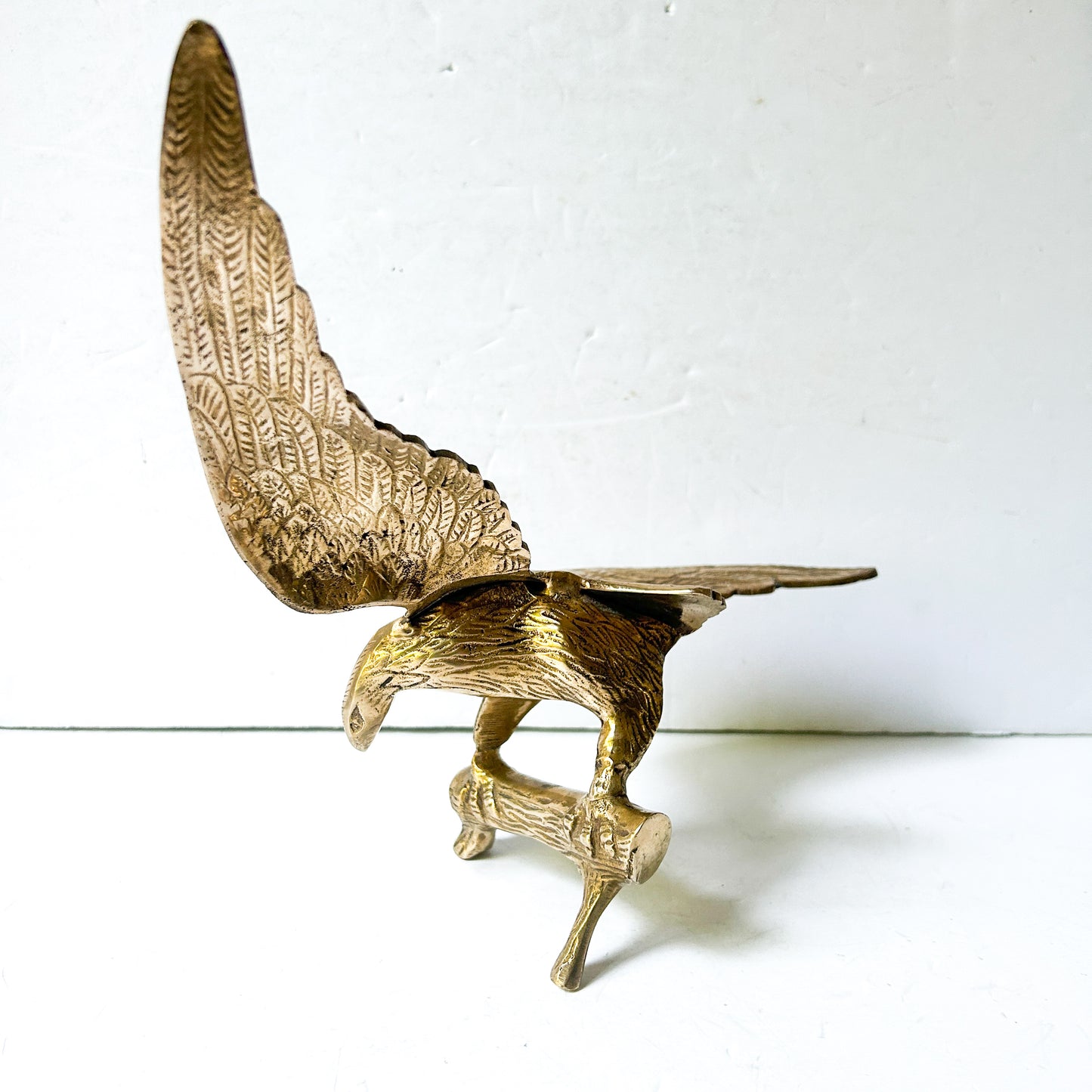 Vintage brass eagle sculpture perched on branch