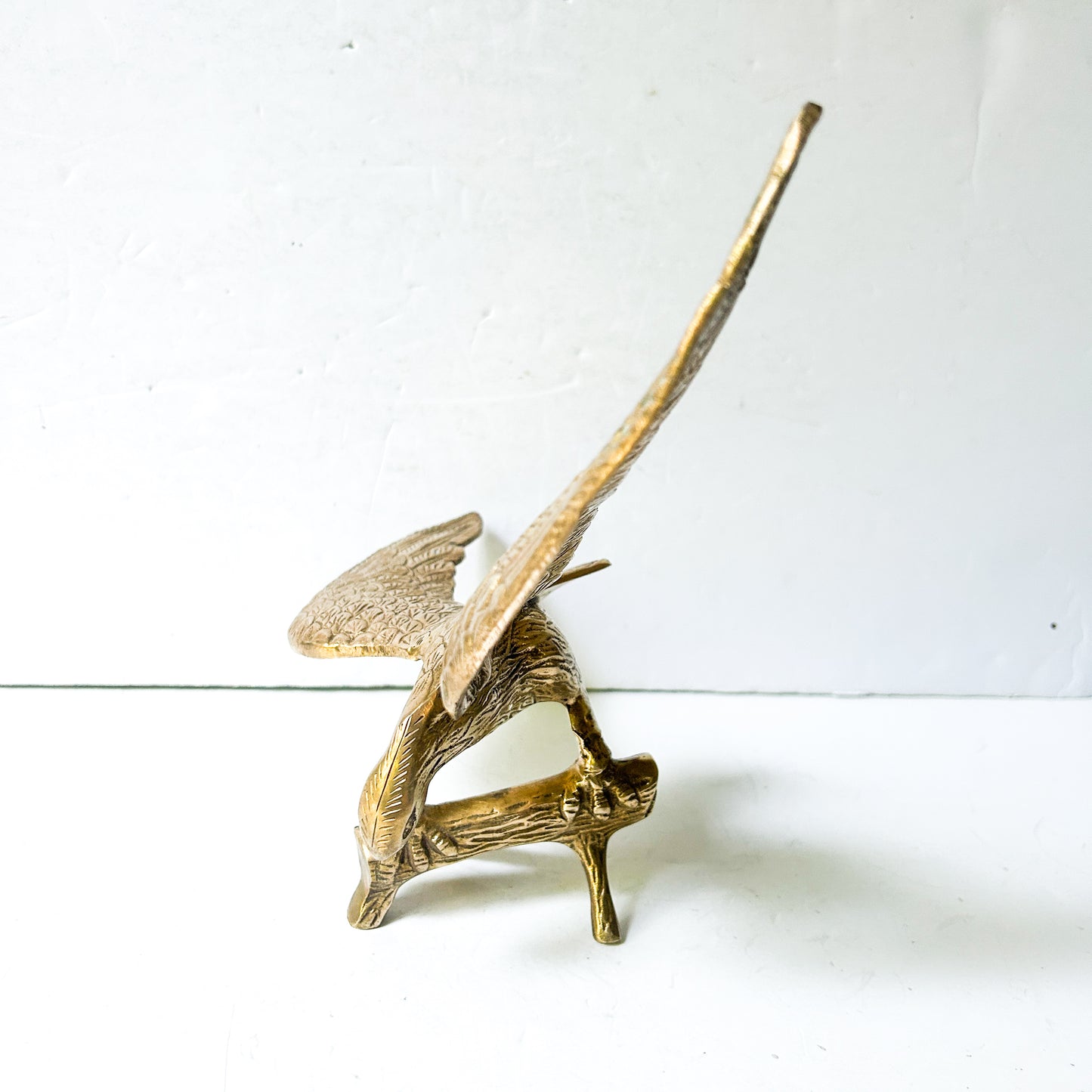 Vintage brass eagle sculpture perched on branch