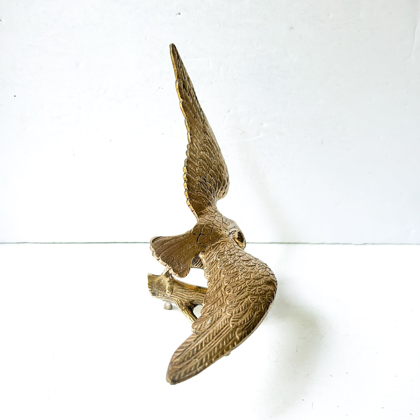 Vintage brass eagle sculpture perched on branch