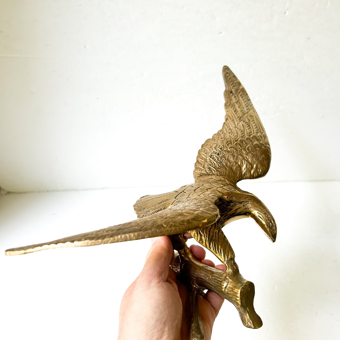 Vintage brass eagle sculpture perched on branch